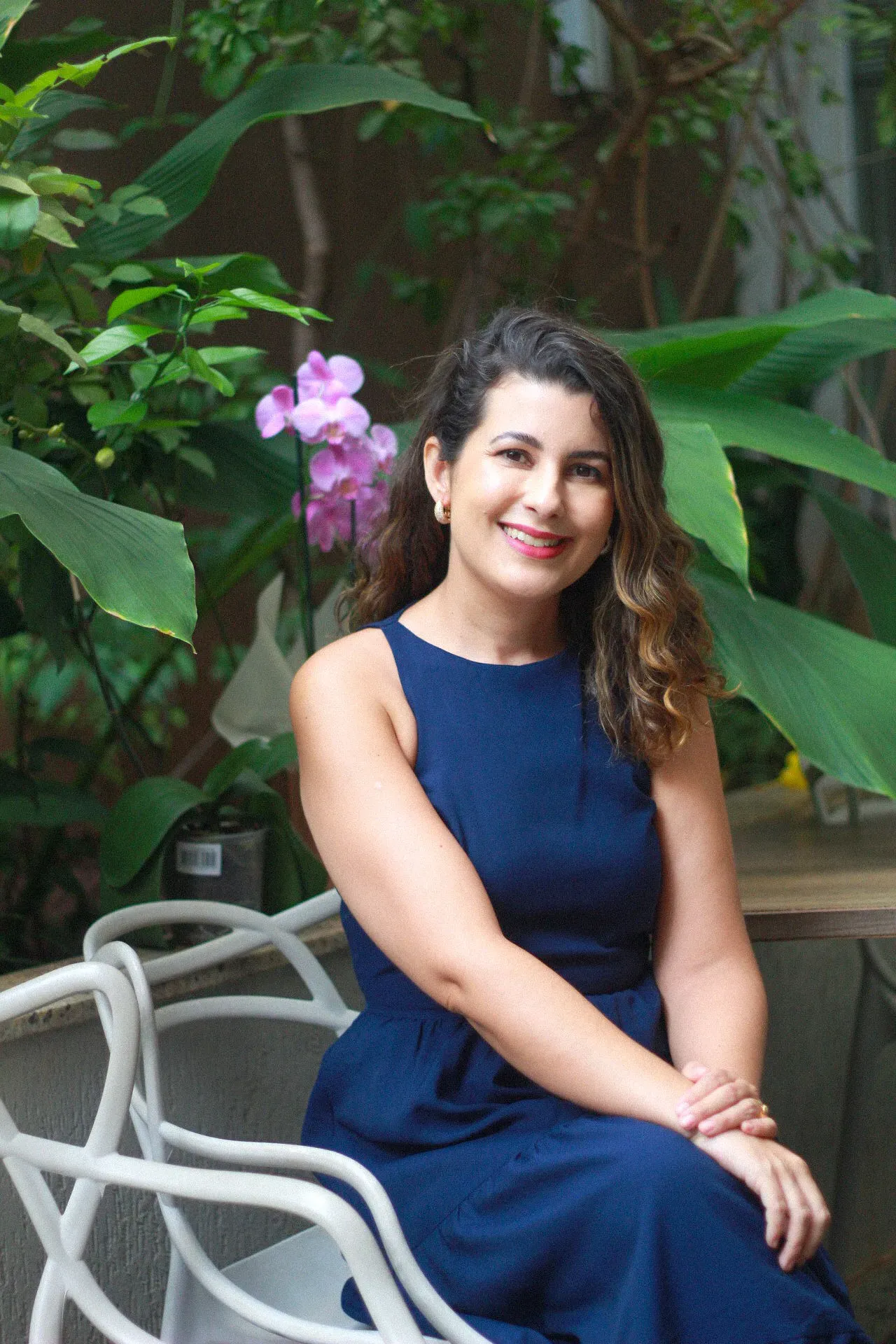 Raquel Eustáquia sentada com orquídeas ao fundo